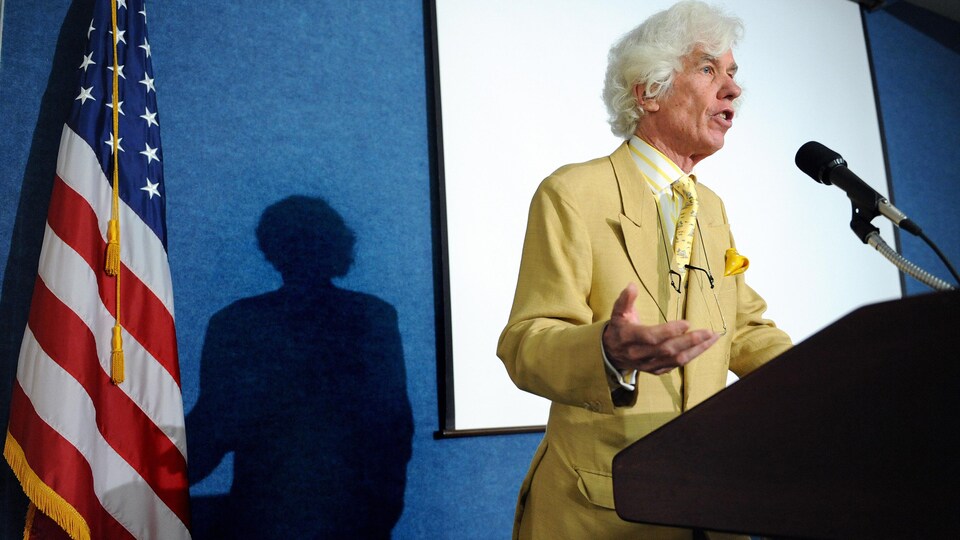 Esmond Bradley-Martin, parlant au micro, devant un lutrin.