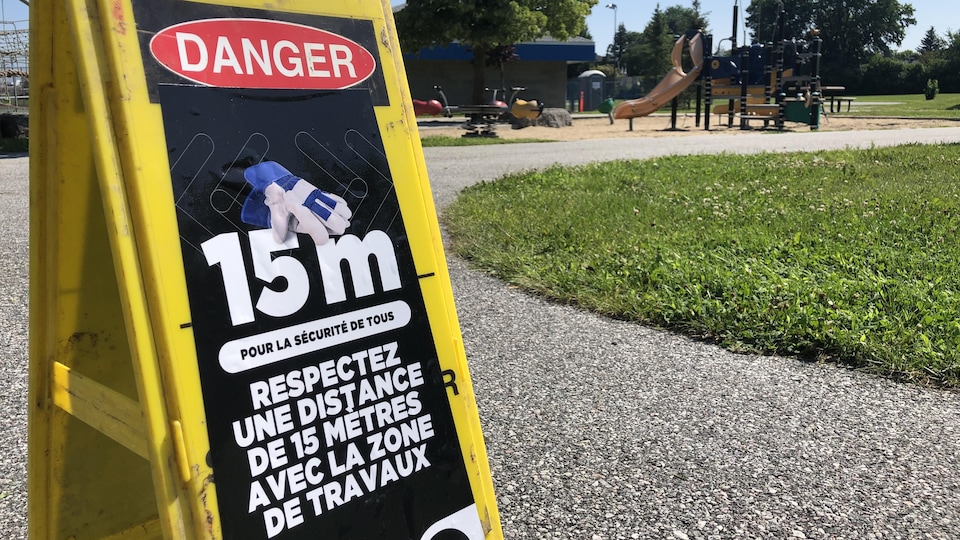 Un panneau dans un parc demandant de respecter une distance de 15 mètres pour des questions de sécurité.