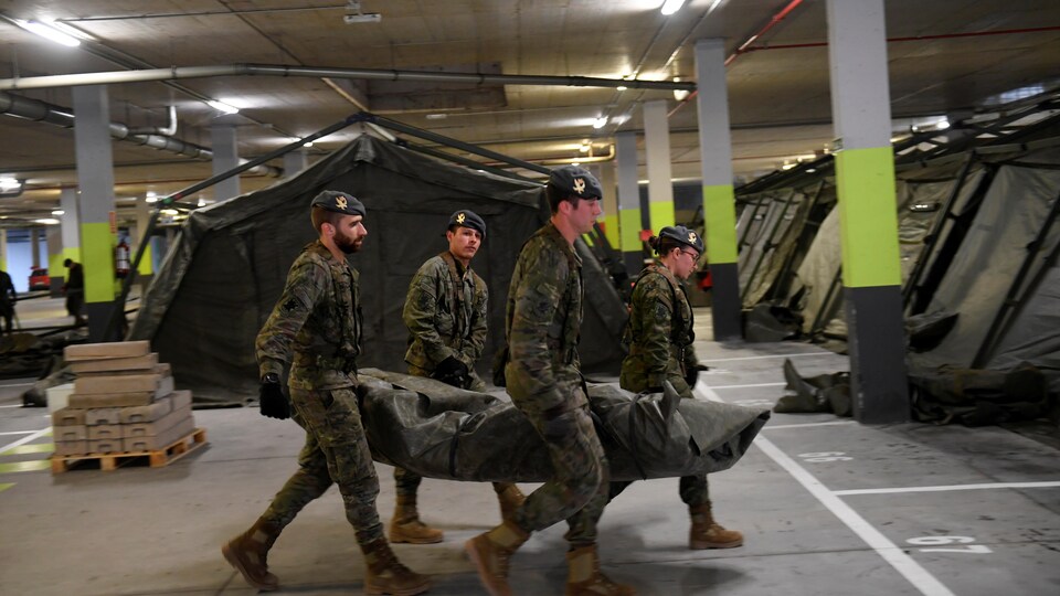 Des soldats transportent des tentes.