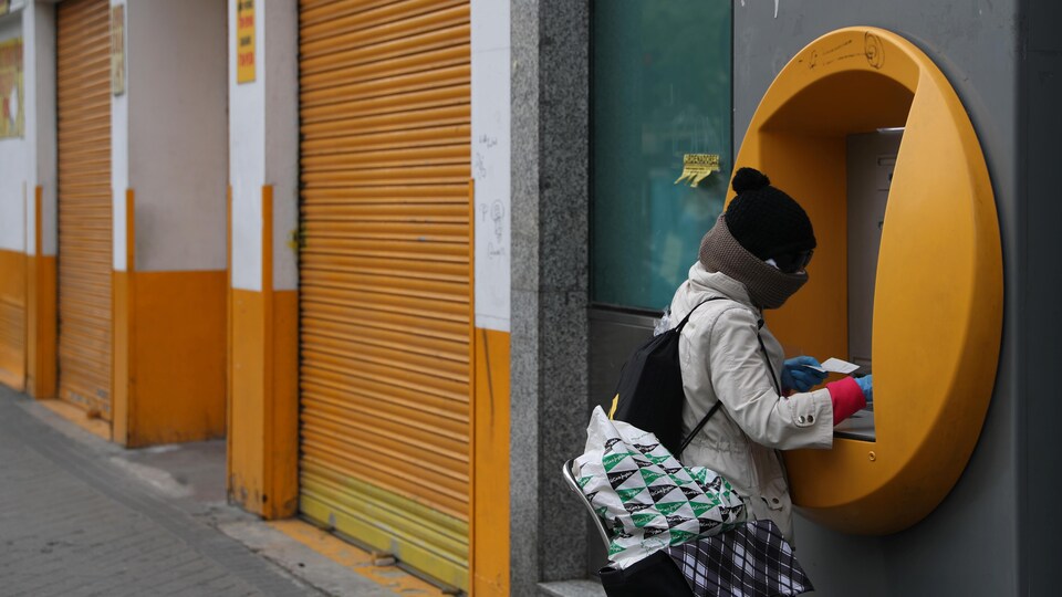 Une femme totalement recouverte retire de l'argent d'un distributeur automatique. 