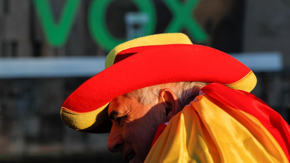 Un partisan du parti d'extrême droite Vox porte un chapeau et une cape aux couleurs de l'Espagne.
