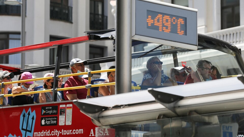 Un autobus touristique passe devant un thermomètre affichant 49 degrés Celsius à Madrid.