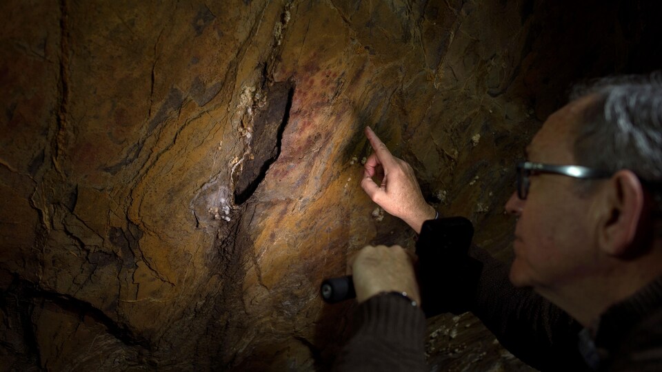 Un scientifique observe la stalagmite de la grotte d'Ardales peinte par des Néandertaliens.