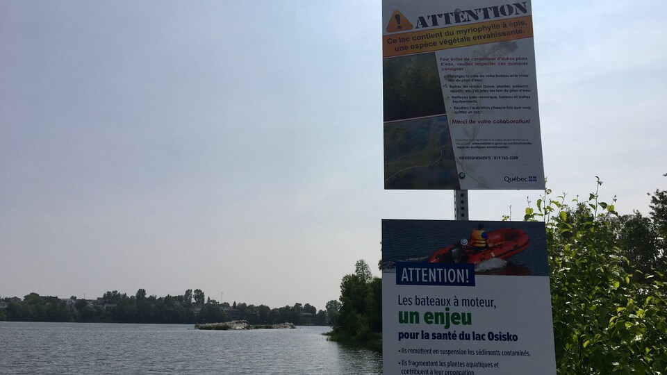Deux panneaux indiquent que le lac à proximité contient du myriophylle à épis. Des détails pour éviter de contaminer d'autres plans d'eau s'y trouvent.