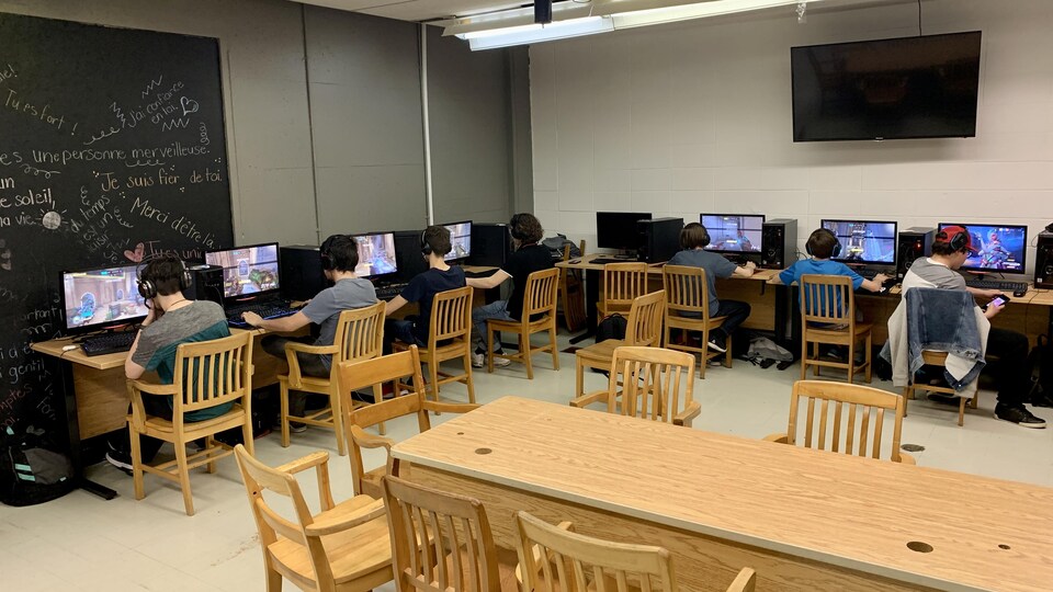 Des élèves devant leur écran d'ordinateur dans un local en train de jouer à un jeu vidéo.