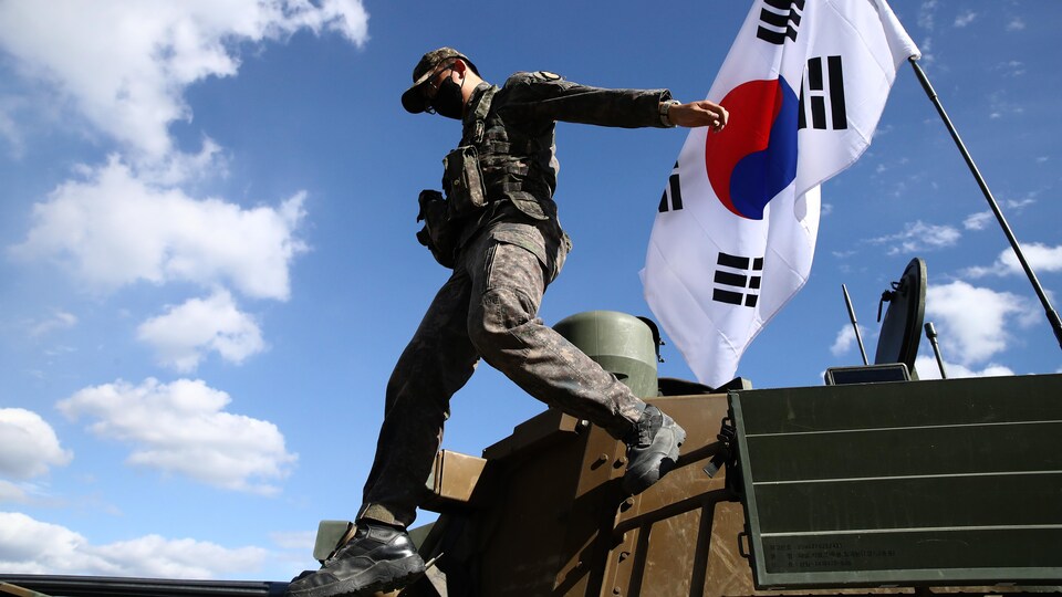 Un membre de l'armée de la Corée du Sud descend d'un char arborant le drapeau du pays. 