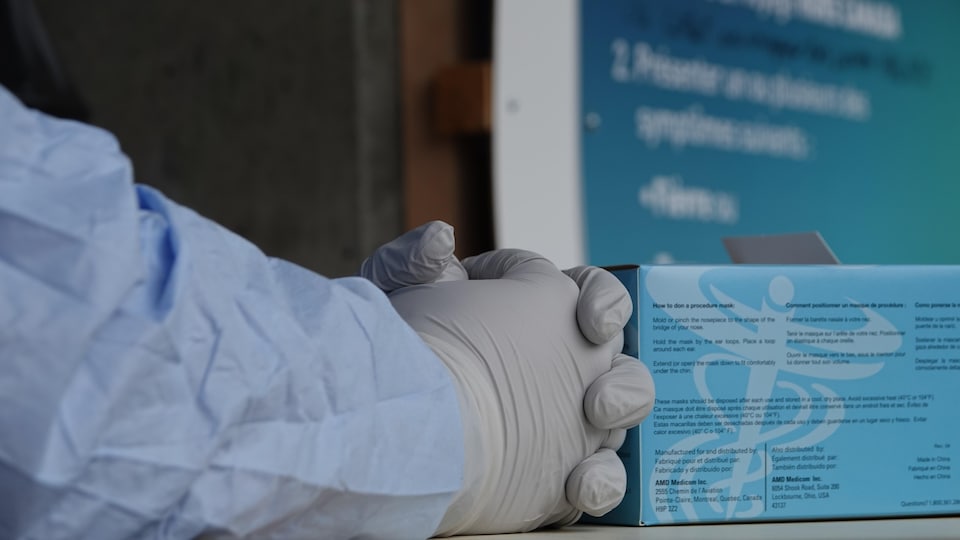 Un employé muni de gants de protection attend les citoyens au centre de dépistage de la COVID-19 à Sherbrooke. 