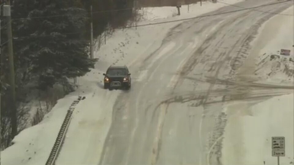 Une voiture immobilisÃ©e sur le bord d'une route de campagne trÃ¨s enneigÃ©e, par temps gris.