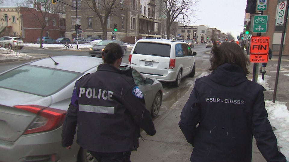 Une policière et une intervenante marchent vers leur voiture de fonction.