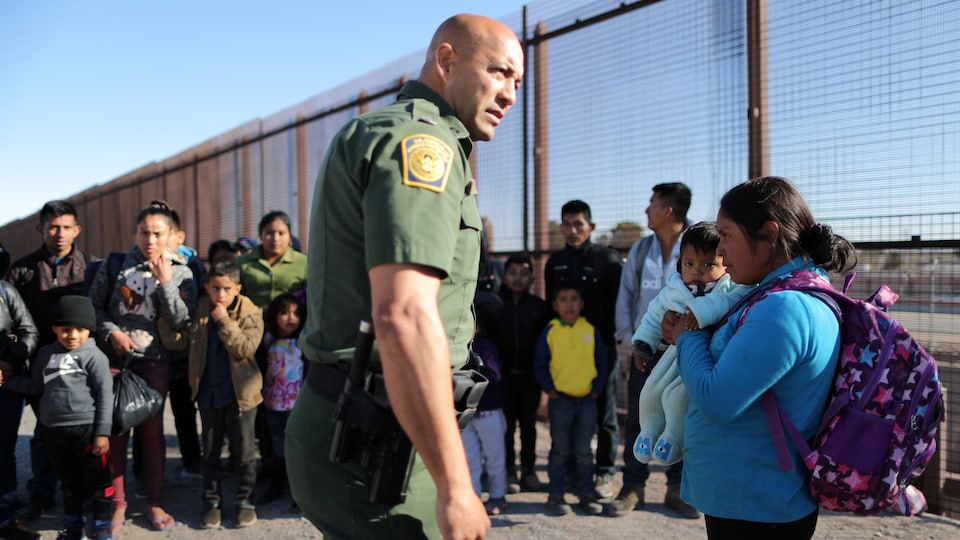 Des gardes frontaliers interrogent des familles de migrants d'Amérique centrale à la frontière entre le Mexique et les États-Unis.