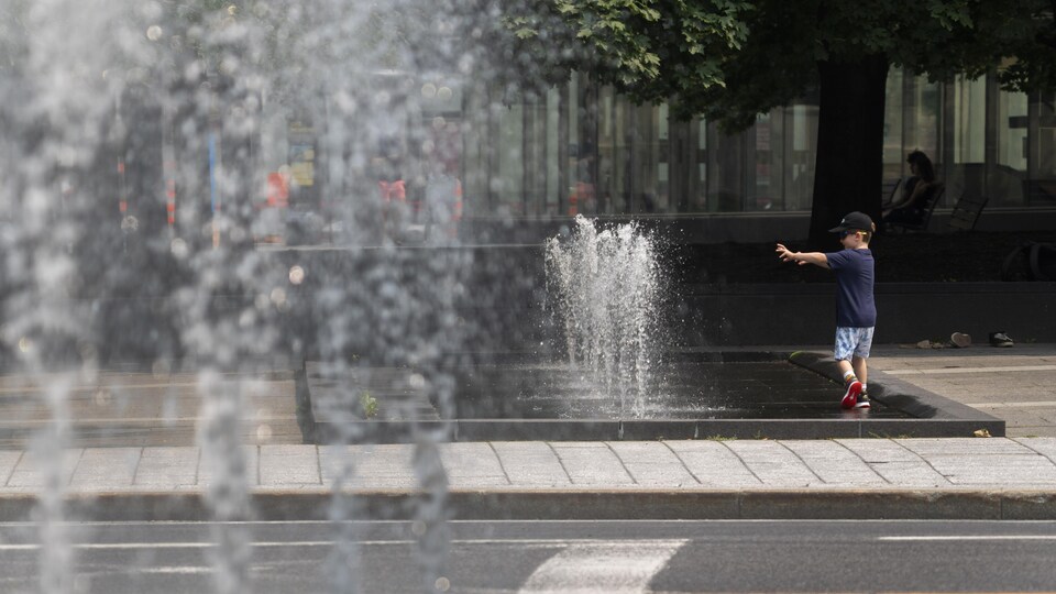 Un enfant marche autour de jets d'eau.