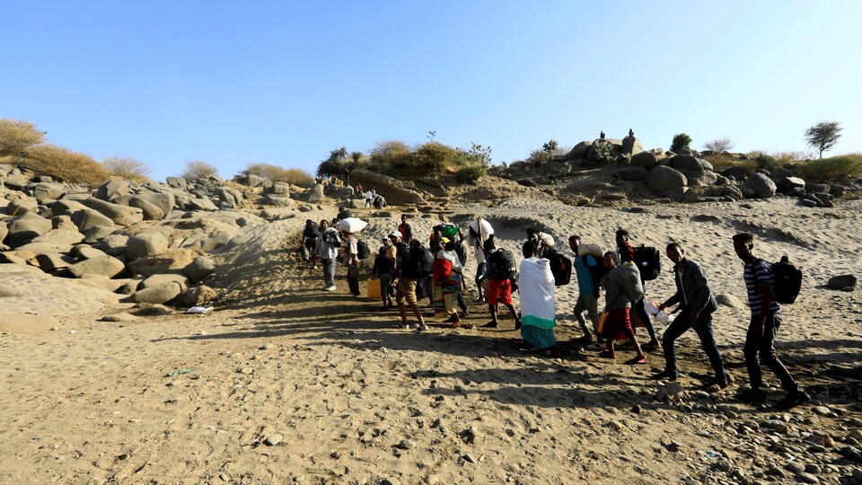 Des Éthiopiens marchent dans le désert avec leurs effets personnels. 