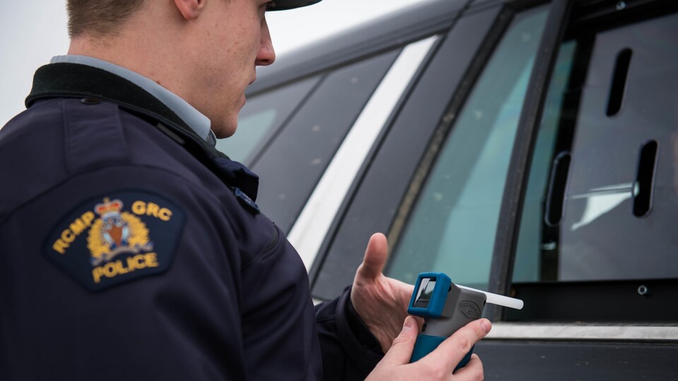 Un policier de la Gendarmerie royale du Canada (GRC) tient un éthylomètre afin de mesurer l'alcoolémie d'un conducteur à un barrage routier.