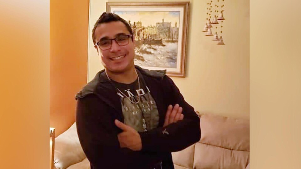 L'homme souriant avec les bras croisés.