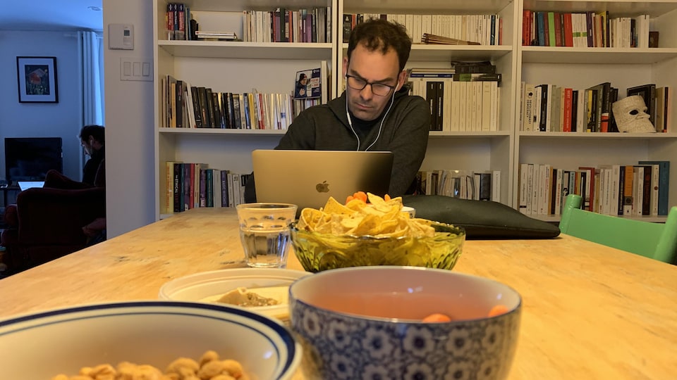 A man sitting at a table, carrying food and a computer.