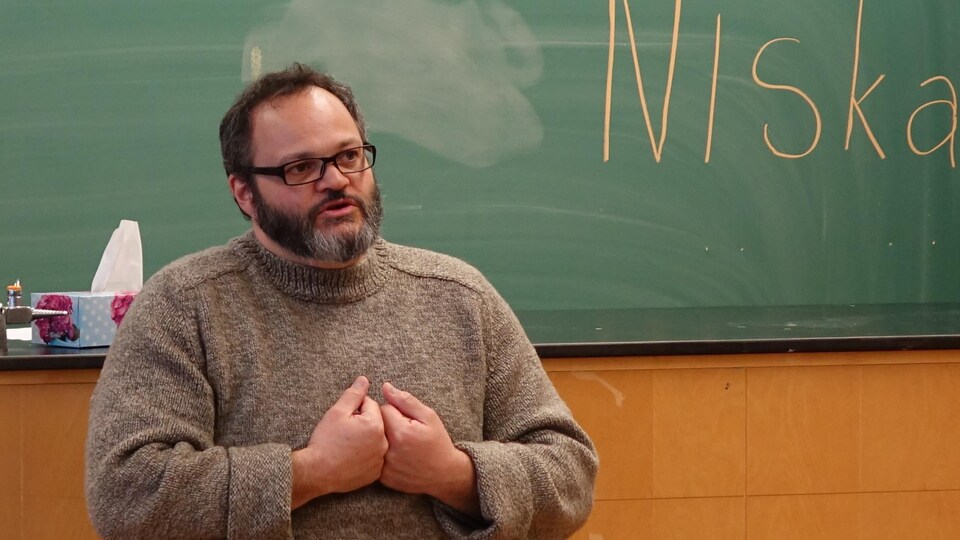 L'auteur Étienne Poirier, assis sur un tabouret devant un tableau noir, lors d'une rencontre avec les jeunes de l'école secondaire Otapi à Manawan en février 2018.