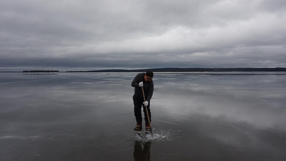 Un homme avec un bâton de bois en main dans l'eau.