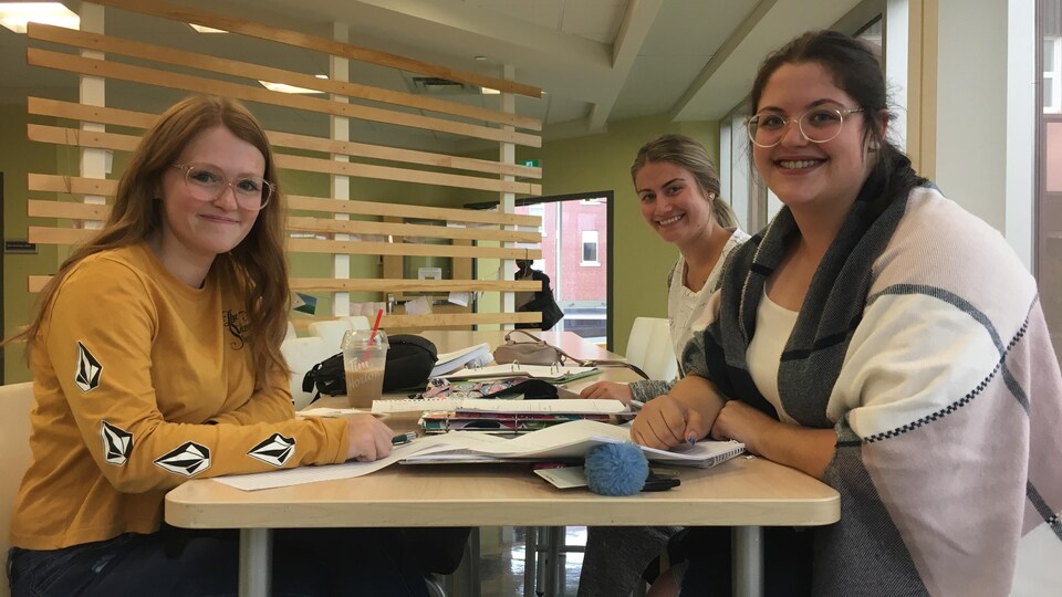 Des jeunes femmes assises autour d'une table sur laquelle il y a plusieurs livres.