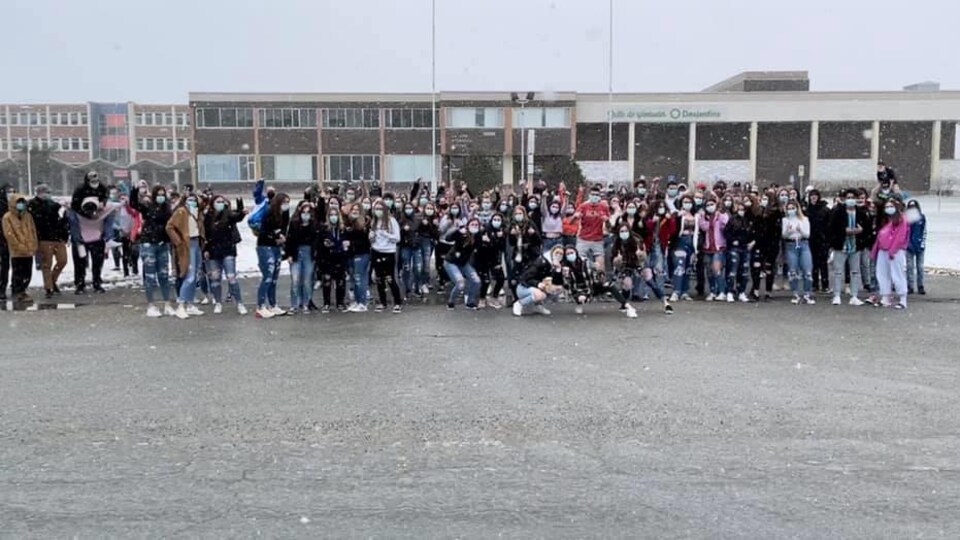 Plusieurs dizaines d'étudiants portant des jeans troués posent devant leur école.