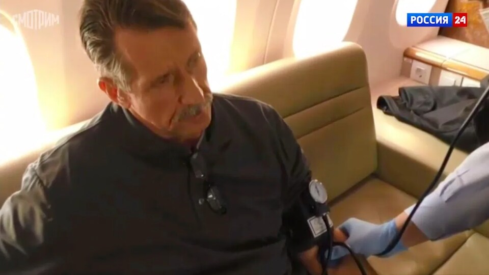 Viktor Bout est assis dans un avion pendant que quelqu'un prend sa pression.