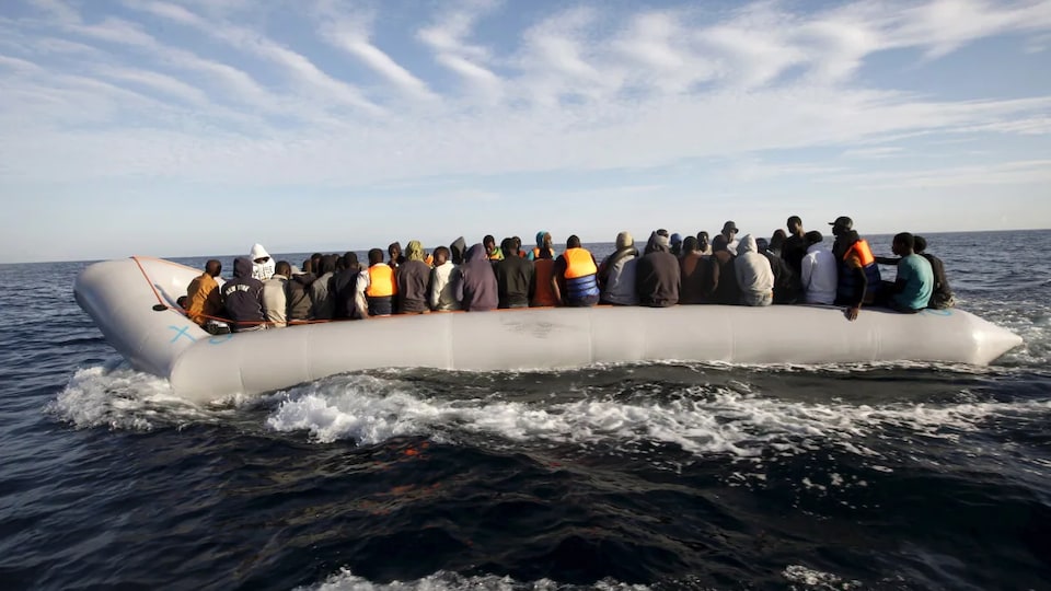 Plusieurs dizaines de migrants à bord d'une embarcation pneumatique.
