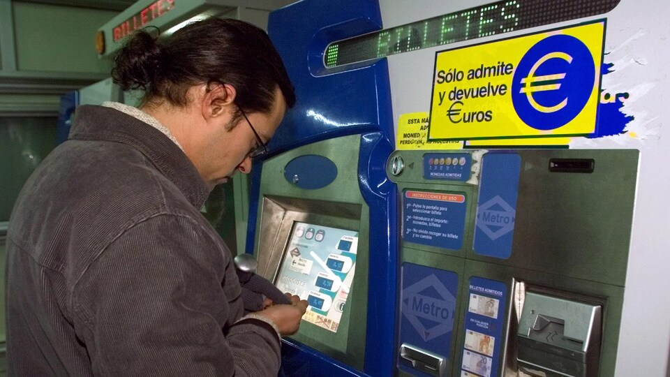 Un homme devant une machine de billets de métro qui accepte les euros à Madrid, en 2002.