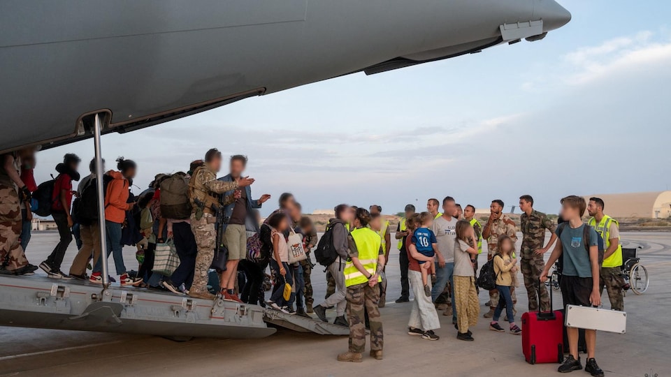 Civilians and soldiers get off a French army plane.