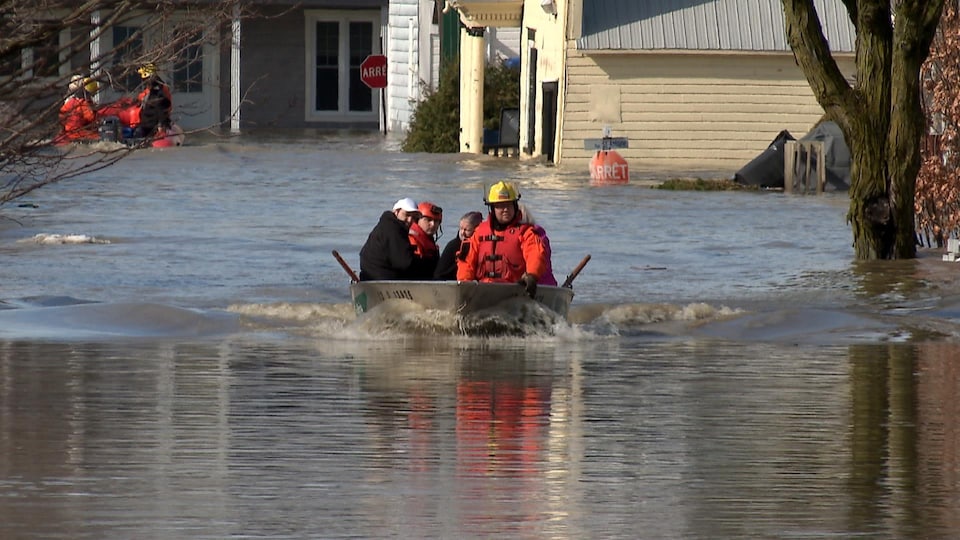 Des secouristes évacuent des résidents à bord d’une chaloupe munie d’un moteur hors-bord dans les rues inondées de Sainte-Marie.
