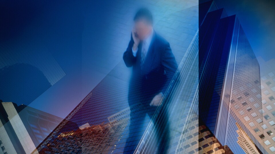 Un homme en complet parle au téléphone cellulaire devant des immeubles de bureaux (montage).