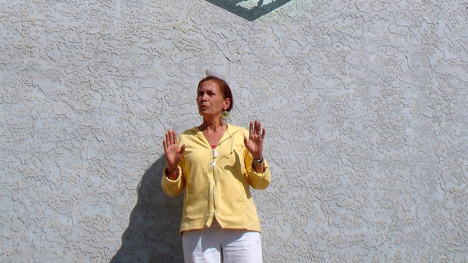 L'artiste fransaskoise Eveline Hamon sous une large sculpture de Joe Fafard à Duck Lake, en Saskatchewan.