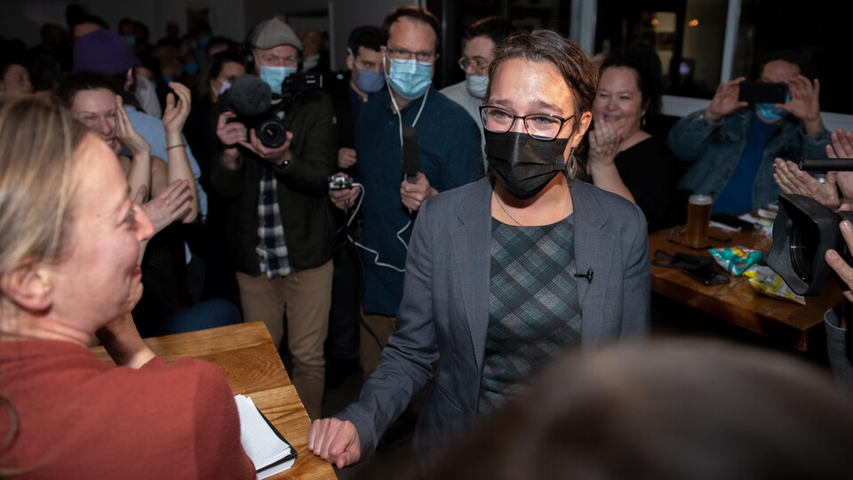 Évelyne Beaudin entourée d'une foule qui l'applaudit.