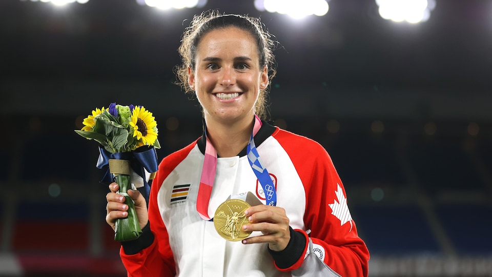 Une athlète tient une médaille d'or en portant l'uniforme canadien.