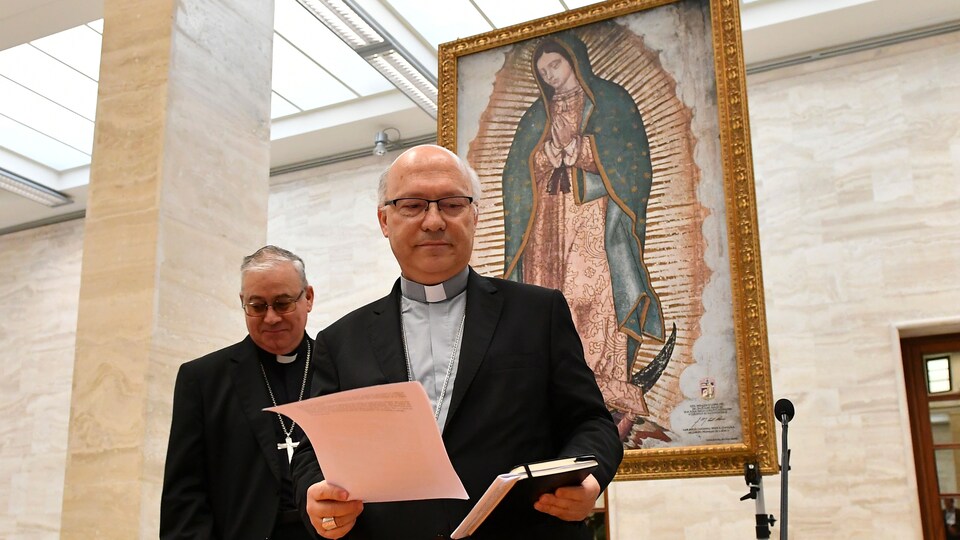 Les deux membres de la conférence épiscopale chilienne arrivent pour leur conférence de presse, donné devant une image religieuse.