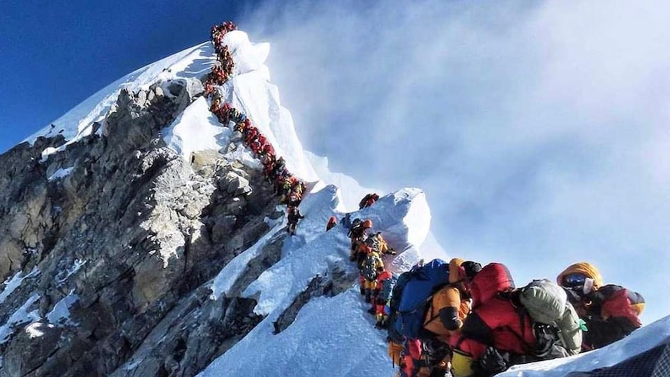 Une longue file d'alpinistes s'étire du sommet de l'Everest.