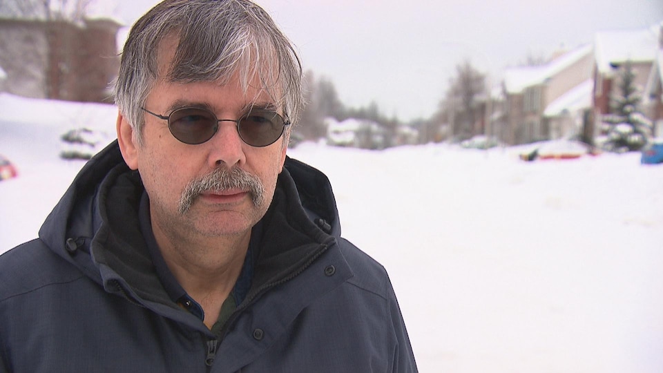 Homme l'hiver avec des lunettes de soleil dans une rue enneigée