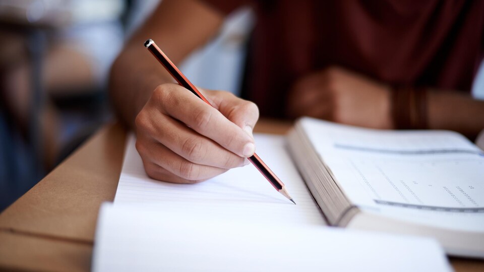 Main d'un étudiant qui prend des notes dans une classe