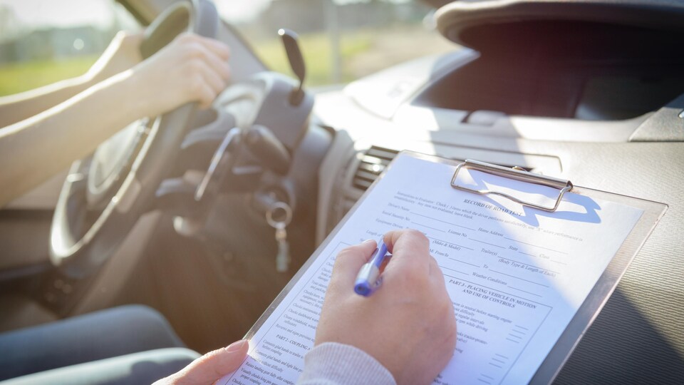 Un évaluateur prend des notes durant un examen de conduite.
