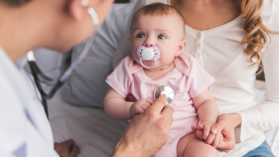 Un pédiatre examine un bébé.