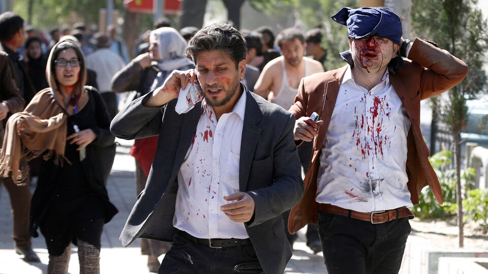 Des blessés fuient les lieux de l'explosion au centre de Kaboul, en Afghanistan.