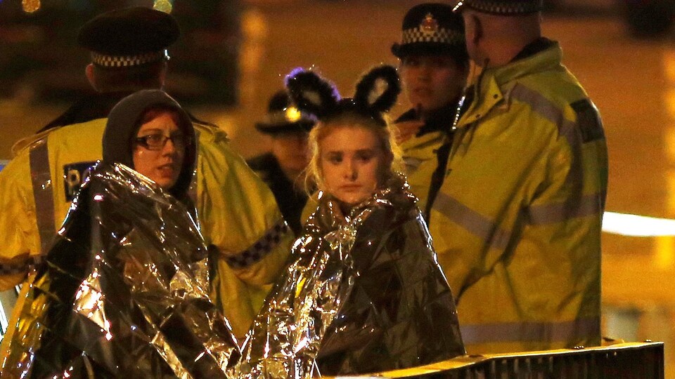 Deux jeunes femmes enveloppées dans des couvertures thermales à la sortie du Manchester Arena
