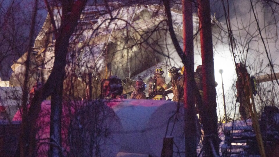 Des pompiers sur la scène de l'incendie à la tombée du jour.