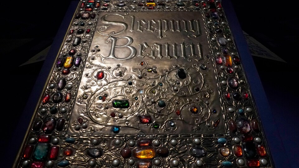 Un grand livre avec les mots Sleeping Beauty est posé sur une table.