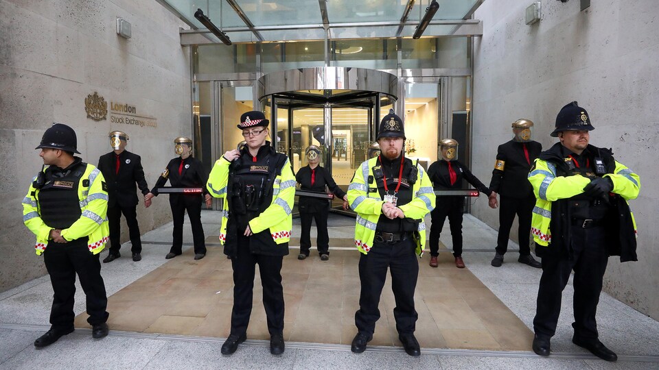 Quatre policiers sont debout devant la rangée de manifestants.