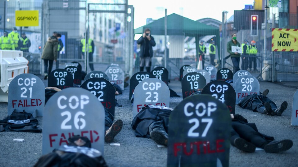 Des gens couchés par terre avec des panneaux qui dénoncent les conférences sur le climat comme des échecs.
