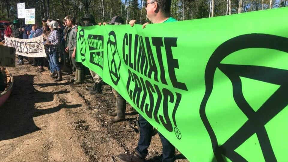 Des manifestants dressent une bannière verte d'Extinction Rebellion.