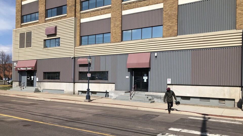 Un homme traverse la rue devant un bâtiment.