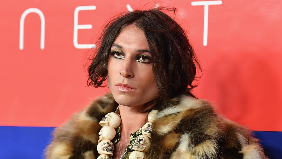 L'artiste porte un manteau de fourrure sur le tapis rouge d'un événement.