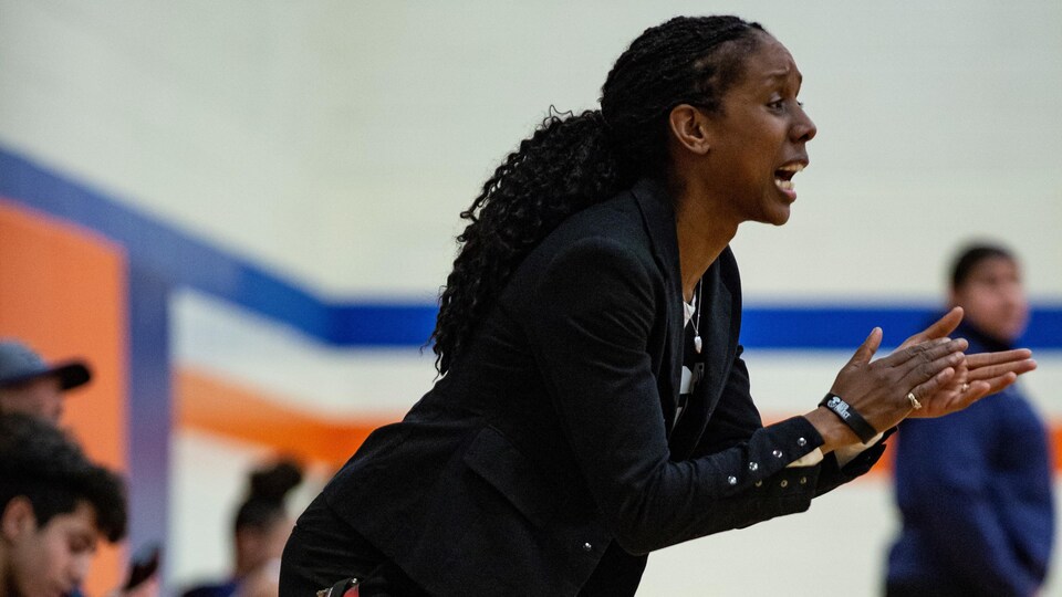 Une entraîneuse encourage ses joueurs pendant une partie de basketball.
