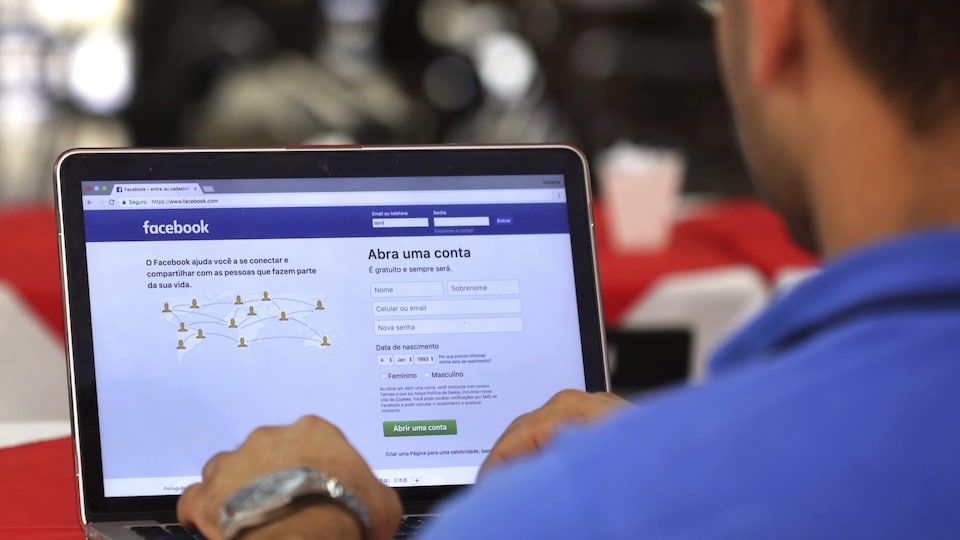 Un homme au clavier d'un ordinateur se branche sur le réseau social Facebook.
