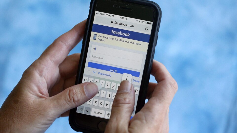 Une personne écrit un message via Facebook sur son cellulaire. 